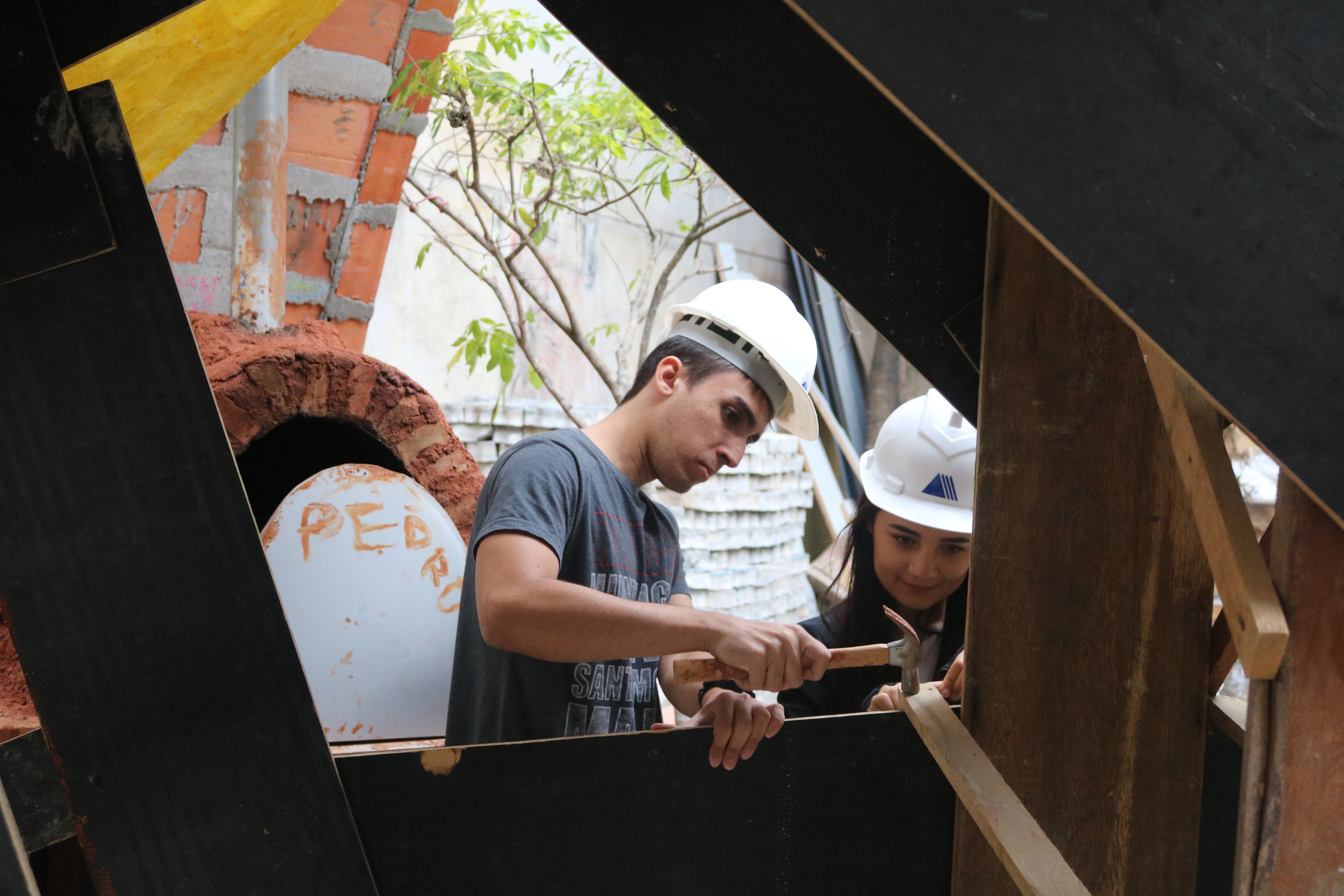 Participantes com capacete trabalhando com estrutura de madeira