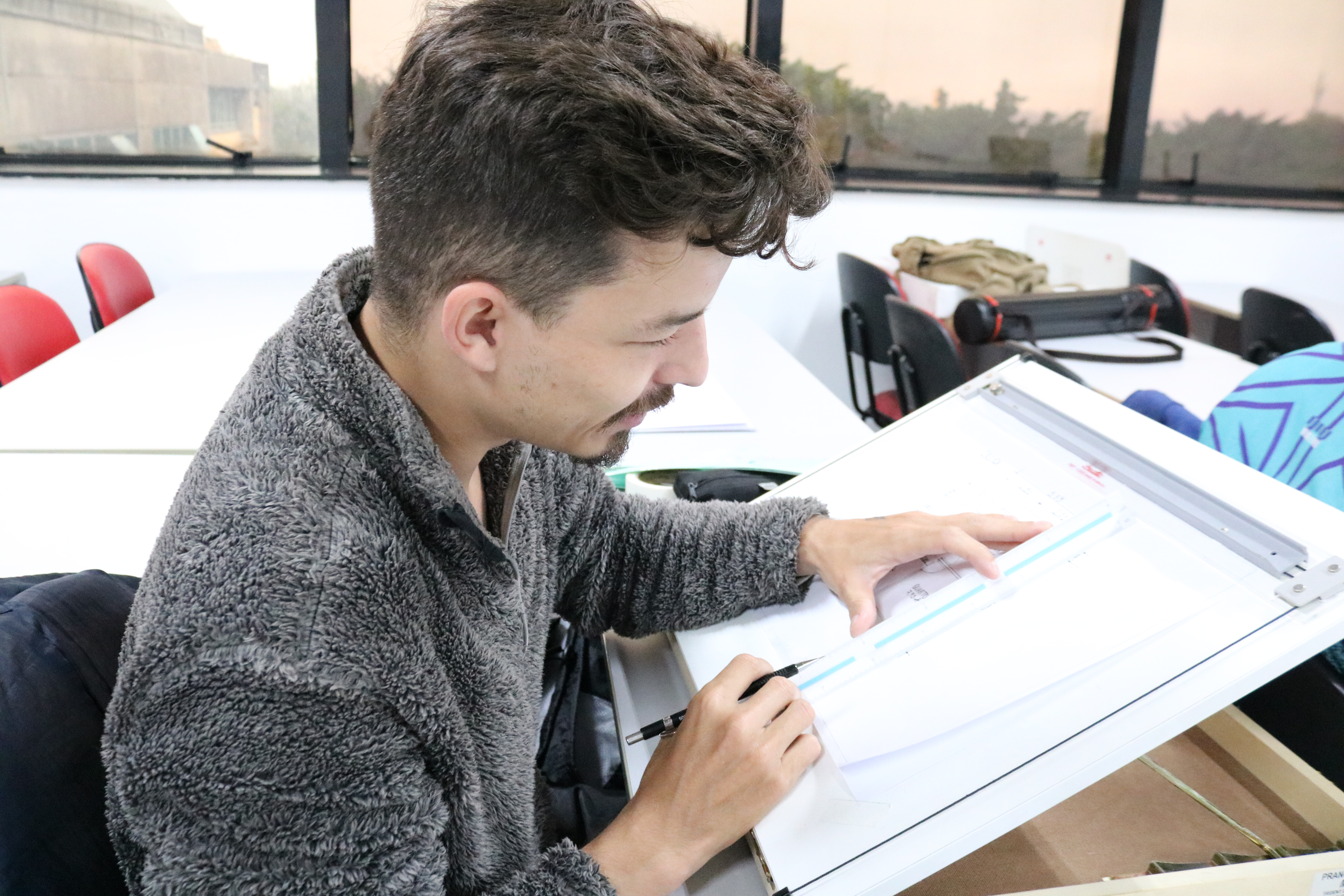 Estudante desenvolvendo desenho técnico em prancheta