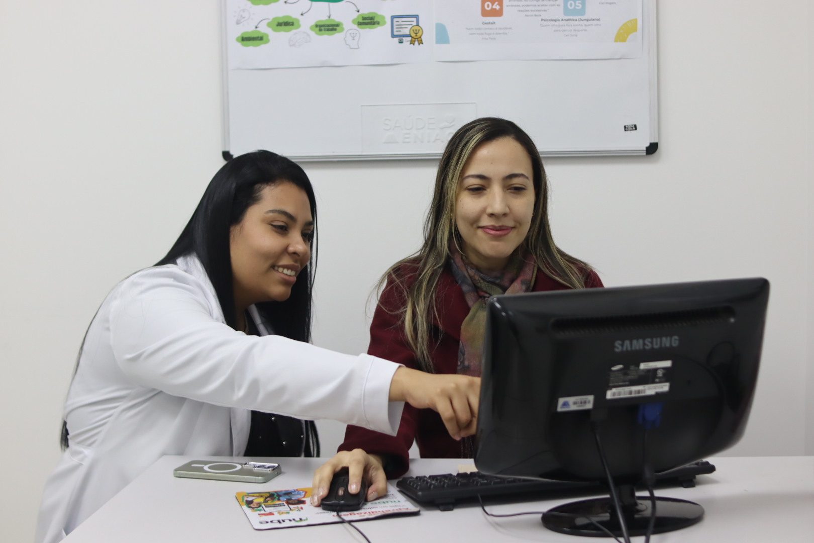 Duas participantes analisando informações em um computador no ambiente clínico